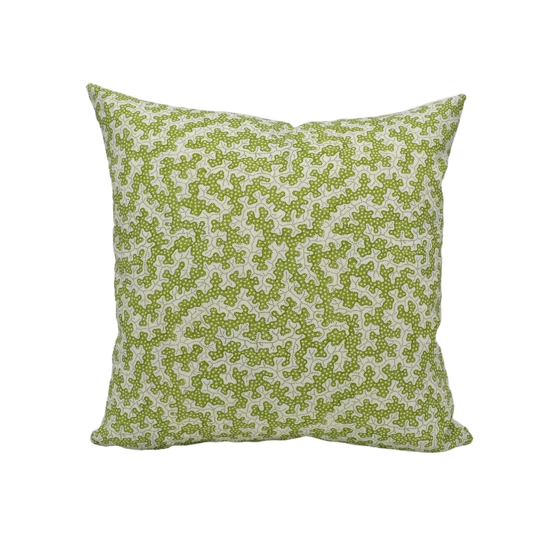 A square throw pillow with a green floral pattern is placed against a white wall.