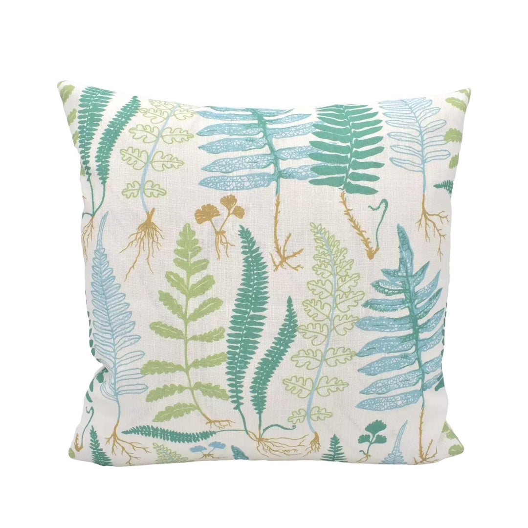 A white pillow with a pattern of green ferns and other plants printed on it.