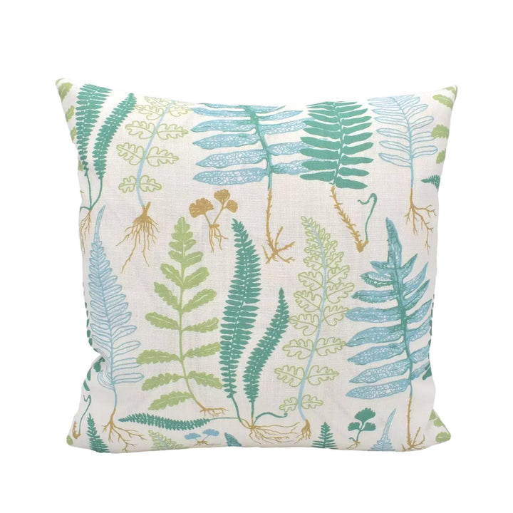 A white pillow with a pattern of green ferns and other plants printed on it.