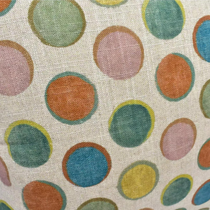 a close-up view of a fabric with a repeating pattern of colorful circles, including shades of green, orange, and pink.