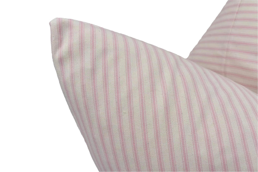A close-up view of a pillow with a striped pattern in shades of pink and white.