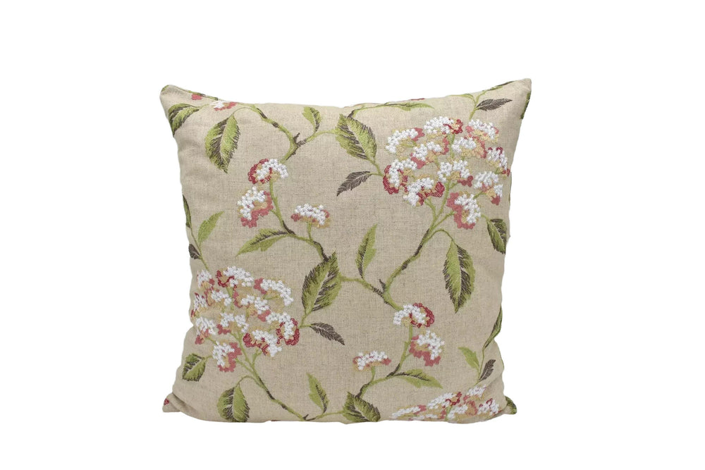 A beige pillow with a floral print design, featuring white flowers and green leaves.