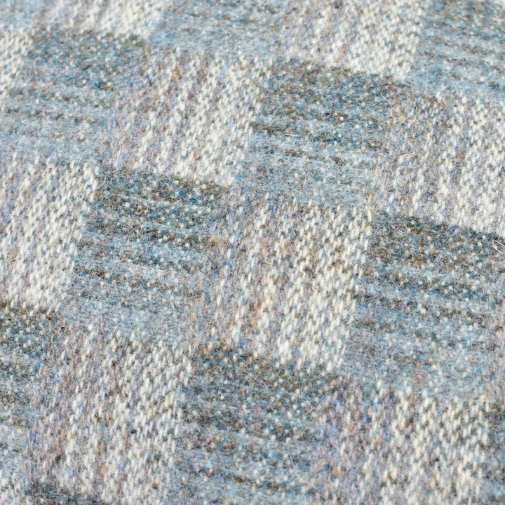 a close-up view of a textured fabric with a geometric pattern of squares and rectangles in shades of blue, gray, and white.