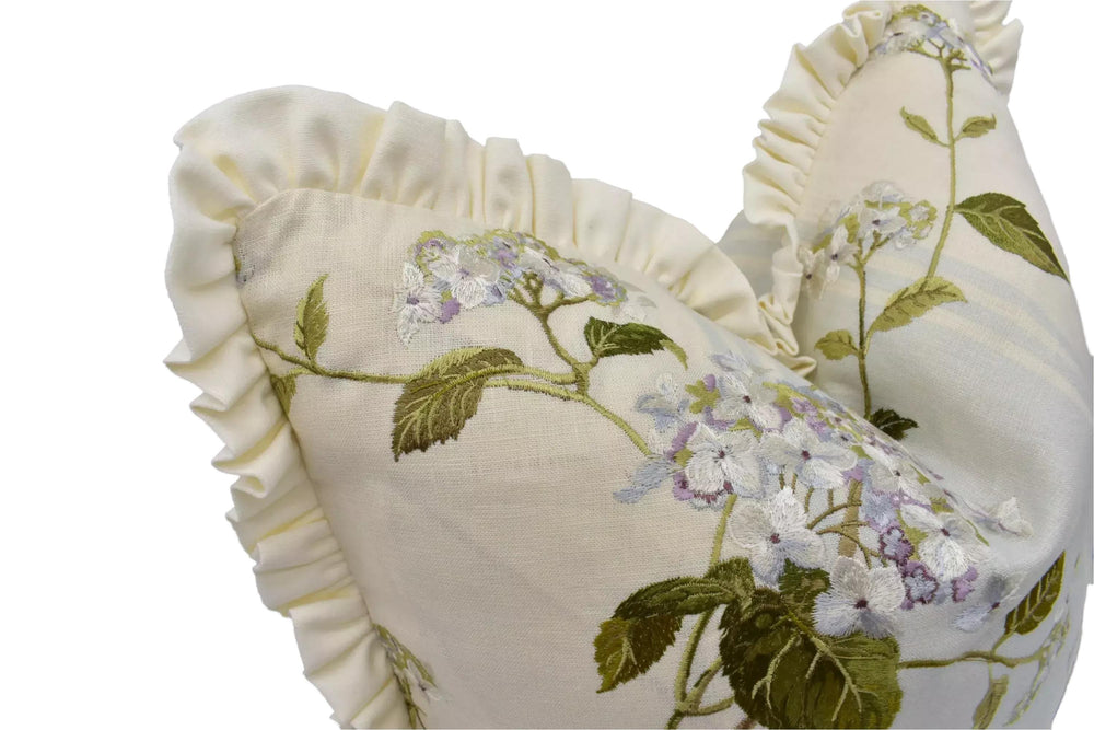 A close-up view of a white fabric with a floral pattern, featuring a ruffled edge and delicate white flowers.