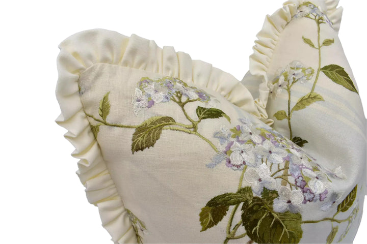 A close-up view of a white fabric with a floral pattern, featuring a ruffled edge and delicate white flowers.