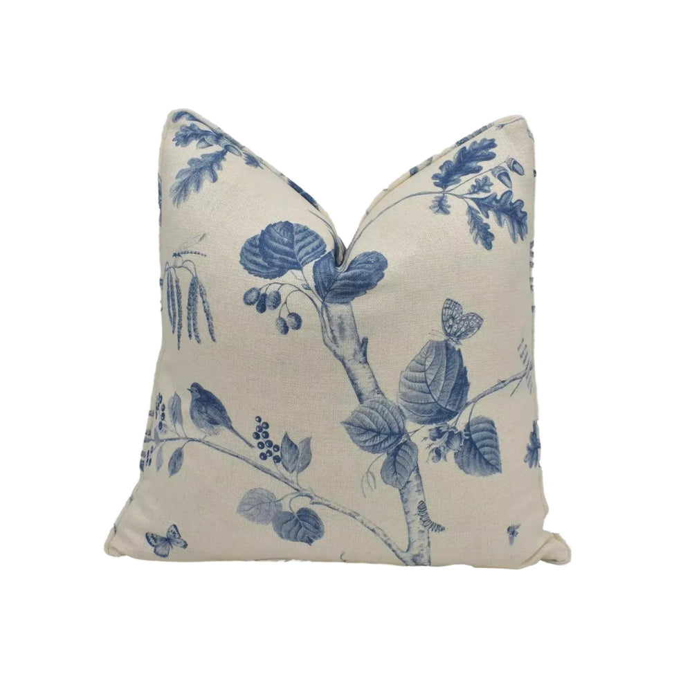 a beige pillow with a blue floral pattern, including leaves, flowers, and birds.