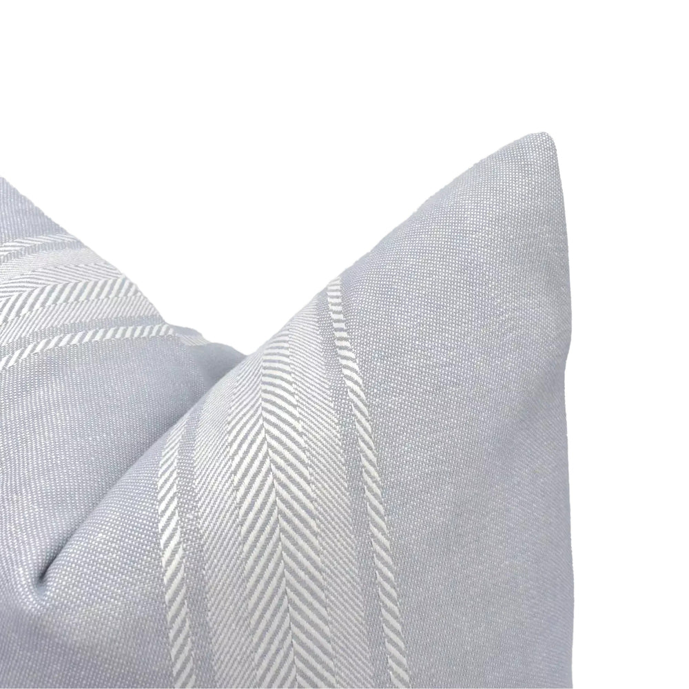 A close-up view of a light blue pillow with a herringbone pattern, set against a plain white background.