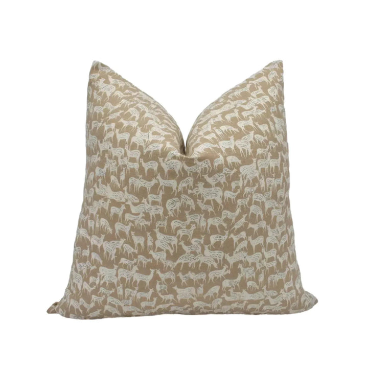 A beige throw pillow with a repeating pattern of white animals, such as zebras and giraffes, against a white background.