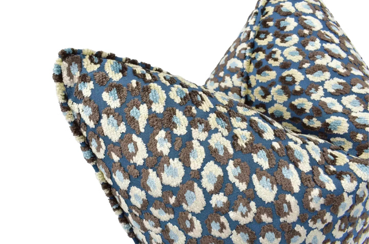 A close-up view of a blue and brown leopard print pillow against a white background.