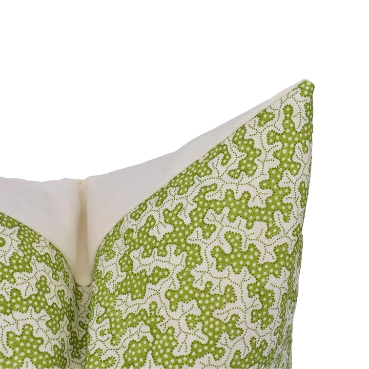 A close-up view of a green and white patterned pillow against a white background.