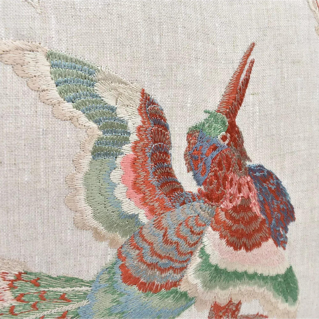 a close-up view of a colorful, intricately embroidered bird with vibrant feathers in shades of red, green, blue, and white.