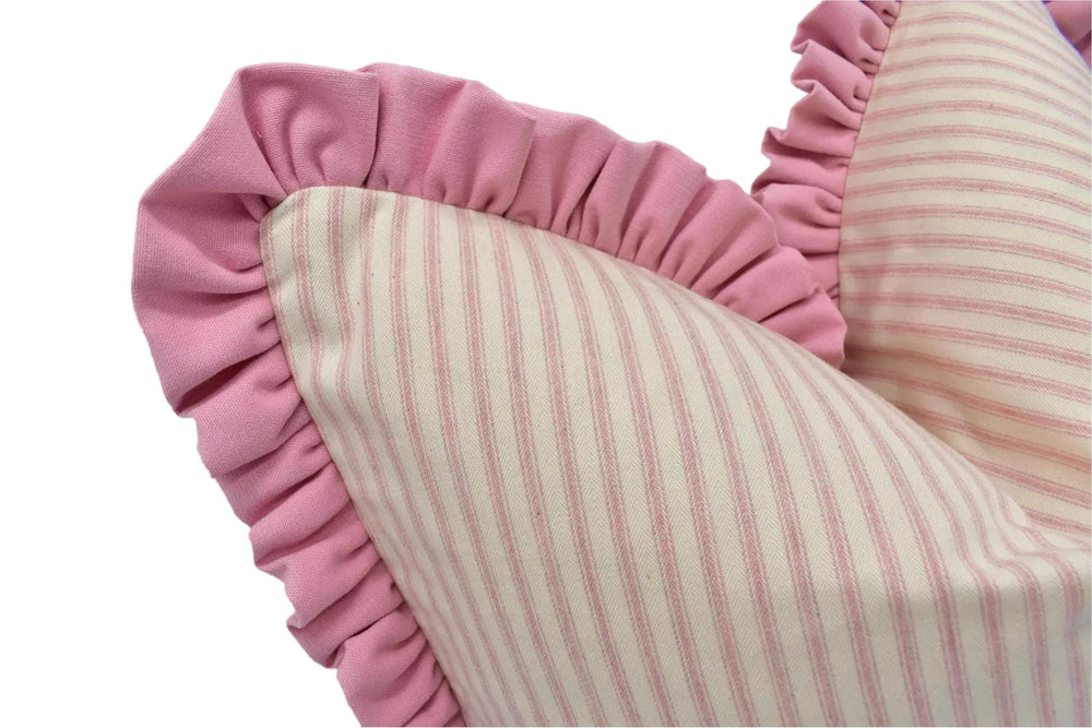 A close-up view of a pink and white striped pillow with a ruffled edge.