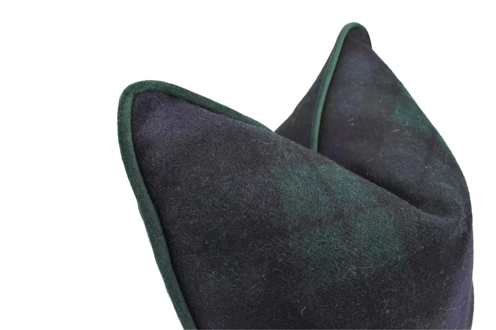 A close-up view of a dark green and black plaid fabric, possibly a pillow or cushion, with a dark green border.