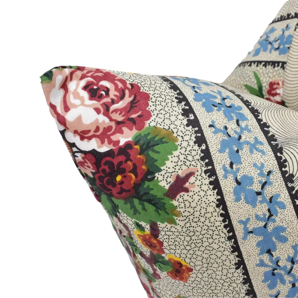 A close-up view of a decorative pillow with a floral pattern, featuring a large red rose and various other colorful flowers.