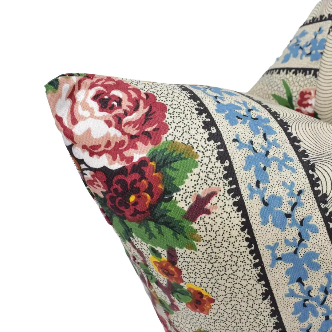 A close-up view of a decorative pillow with a floral pattern, featuring a large red rose and various other colorful flowers.