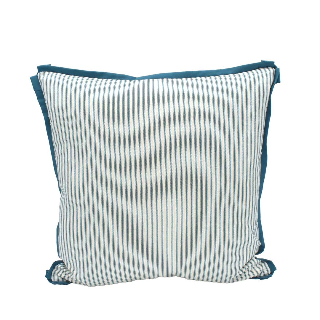 A striped throw pillow with a teal trim is placed against a white wall.