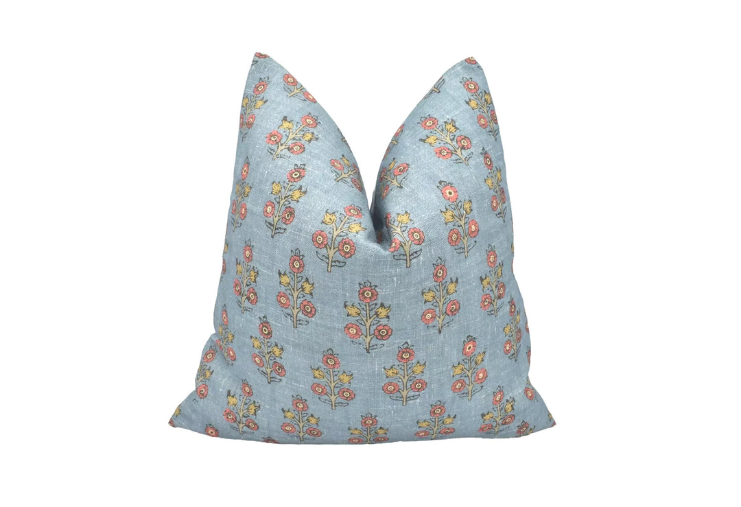 A blue throw pillow with a floral pattern is placed against a white background.