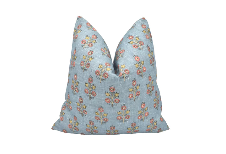 A blue throw pillow with a floral pattern is placed against a white background.