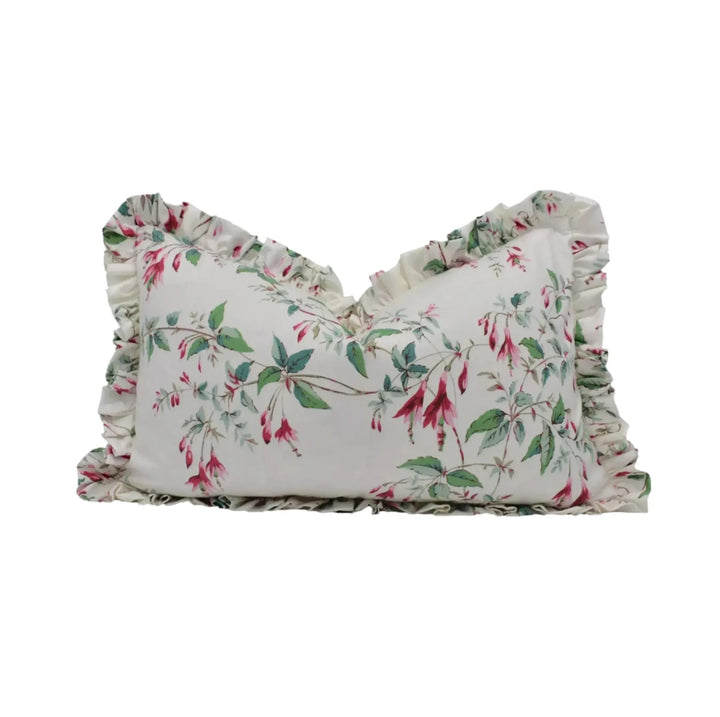 A white pillow with a floral print design, featuring green leaves and pink flowers, is displayed against a white background.
