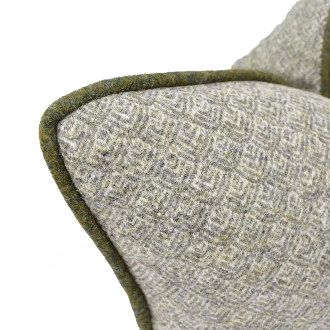 a close-up view of a gray and green patterned fabric, possibly a cushion or a blanket, with a green border or edge.
