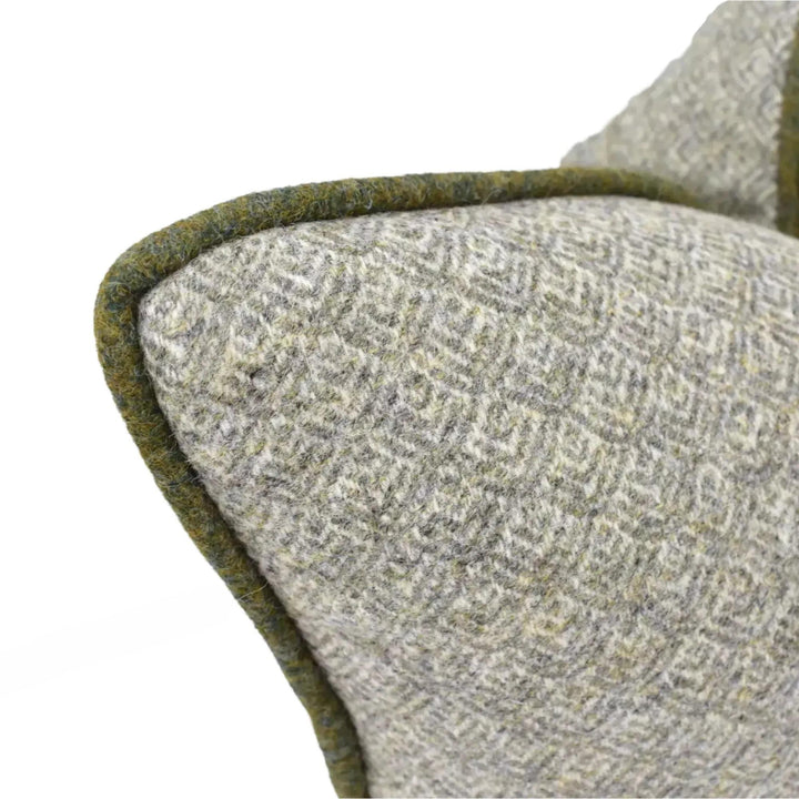 a close-up view of a gray and green patterned fabric, possibly a cushion or a blanket, with a green border or edge.