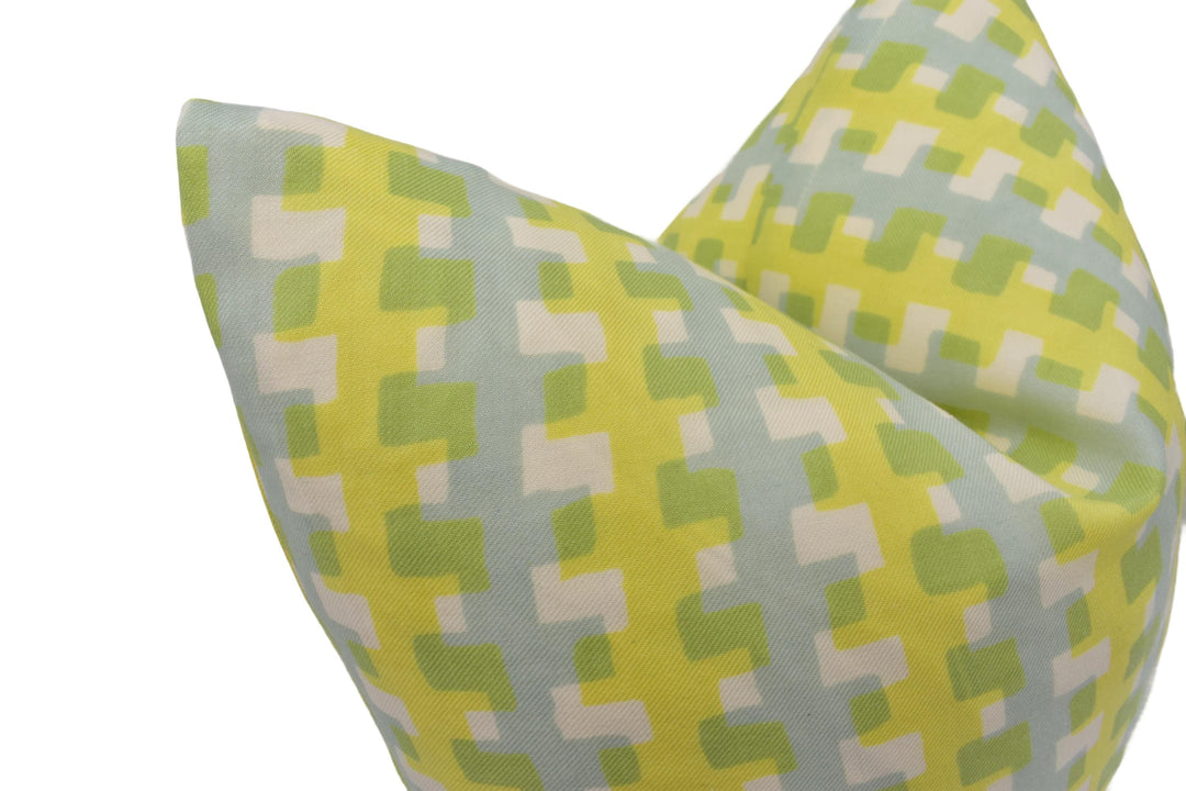 a close-up view of a yellow and green patterned pillow, with a geometric design of squares and rectangles in various shades of green and yellow.
