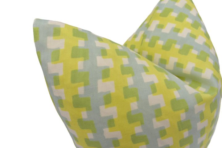 a close-up view of a yellow and green patterned pillow, with a geometric design of squares and rectangles in various shades of green and yellow.