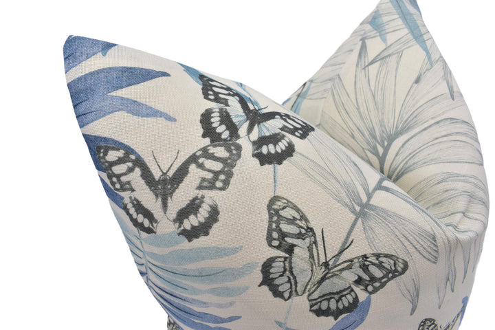 a close-up view of a decorative pillow with a blue and white floral pattern, including butterflies and leaves.