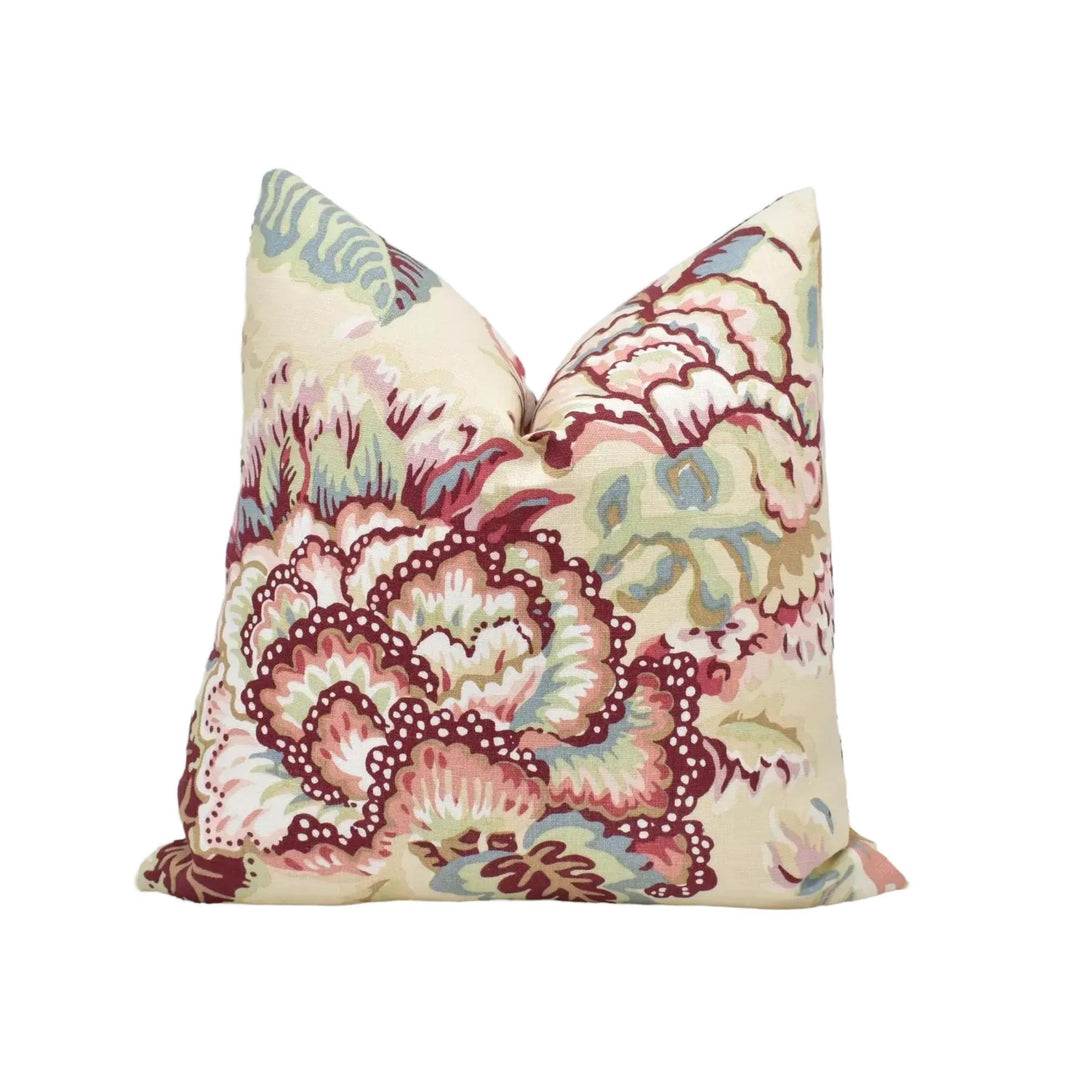 A decorative throw pillow with a floral pattern in shades of pink, red, and green.