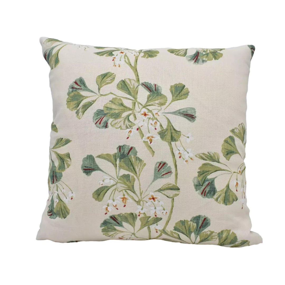 A square throw pillow with a floral print design featuring green leaves and white flowers.