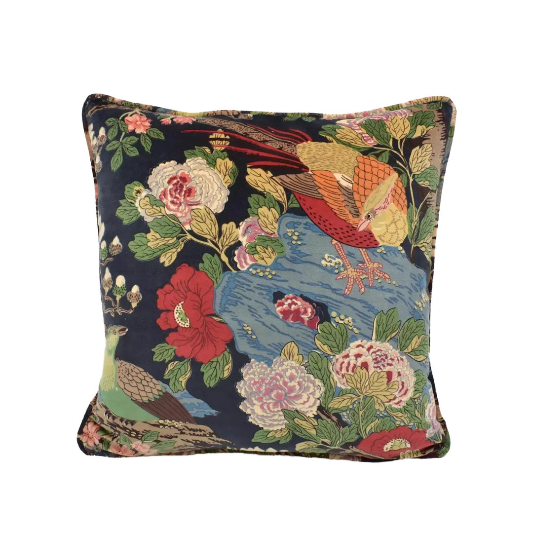 a square throw pillow with a vibrant floral and bird pattern in shades of red, green, and yellow.