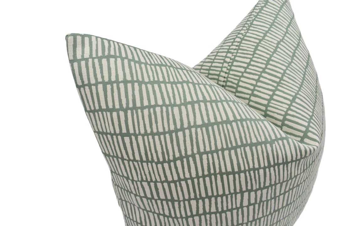 a close-up view of a green and white patterned pillow, with a repeating diagonal line design.