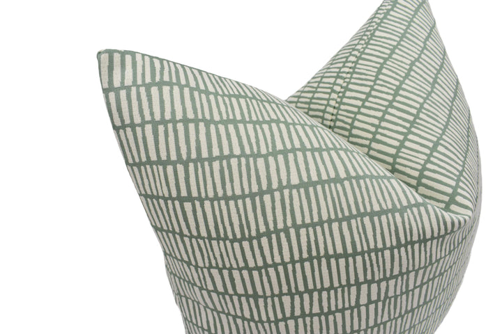 a close-up view of a green and white patterned pillow, with a repeating diagonal line design.