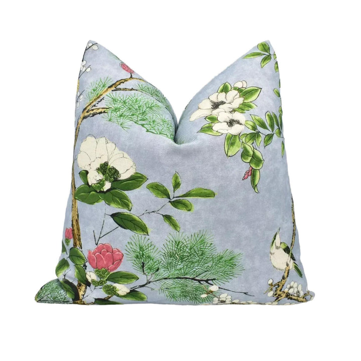 A gray pillow with a floral print design featuring white flowers, green leaves, and pink flowers.