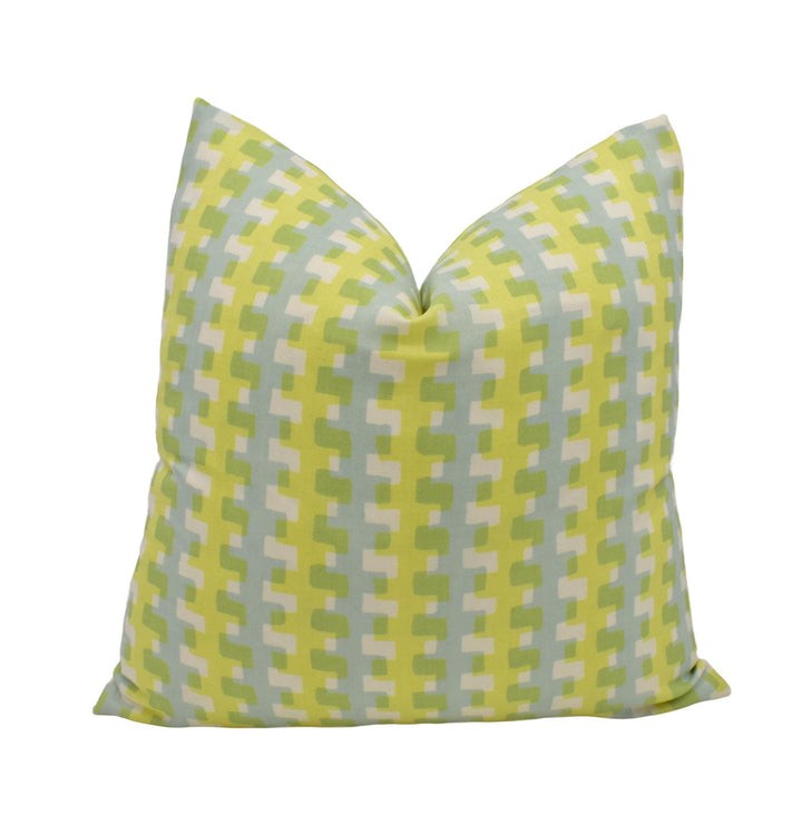 A yellow and green patterned pillow against a white background.