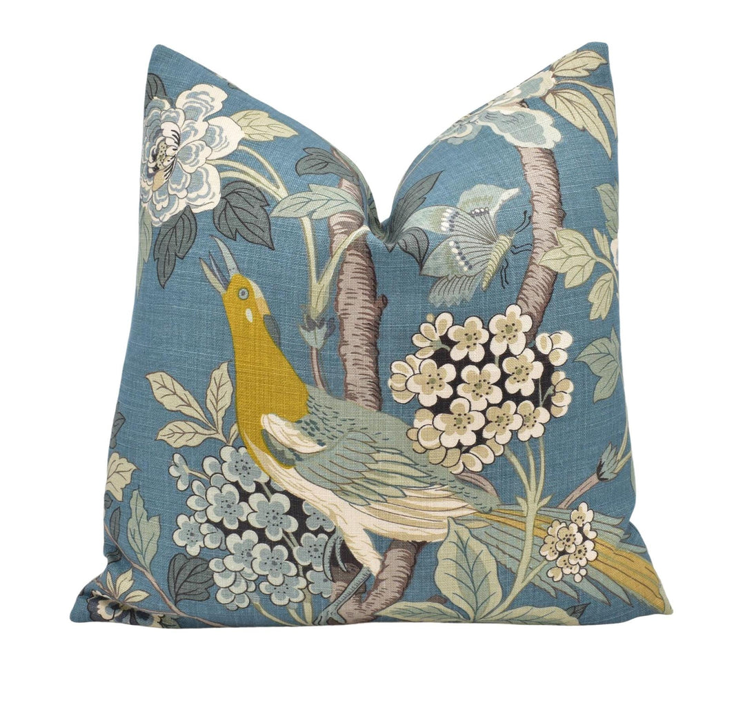 a blue pillow with a bird and flowers on it