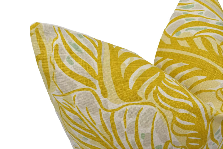 a close-up view of a yellow and white patterned fabric, possibly a pillow or cushion, with a repeating leaf-like design.