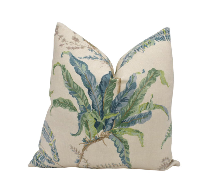 a decorative pillow with a leafy plant design in shades of green and blue.
