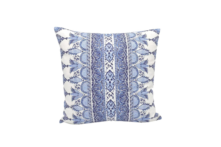 A decorative blue and white patterned throw pillow is placed against a white wall.