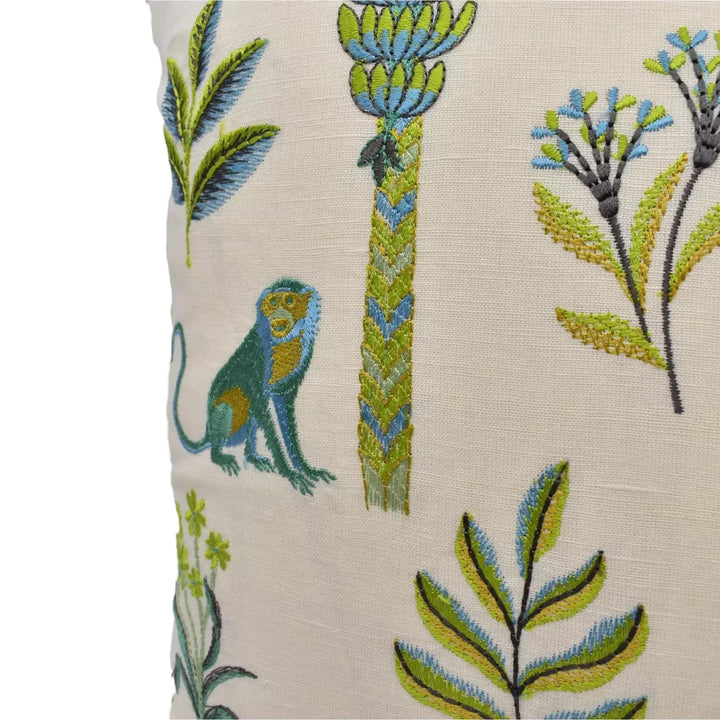 a close-up view of a decorative pillow with various colorful and intricate embroidered designs, including a monkey, palm trees, flowers, and leaves.