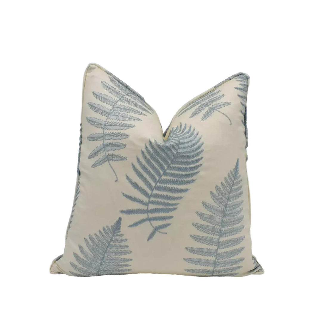 A white pillow with a repeating pattern of blue fern leaves.