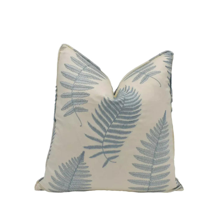 A white pillow with a repeating pattern of blue fern leaves.