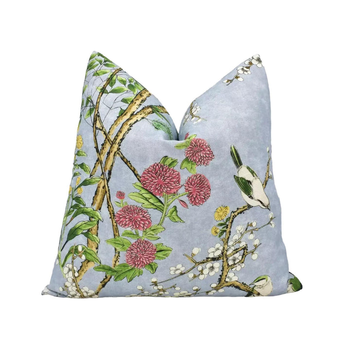 A decorative pillow with a floral pattern featuring pink flowers, green leaves, and a bird perched on a branch.