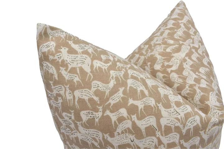 a close-up view of a beige fabric with a repeating pattern of white deer or antelope figures.