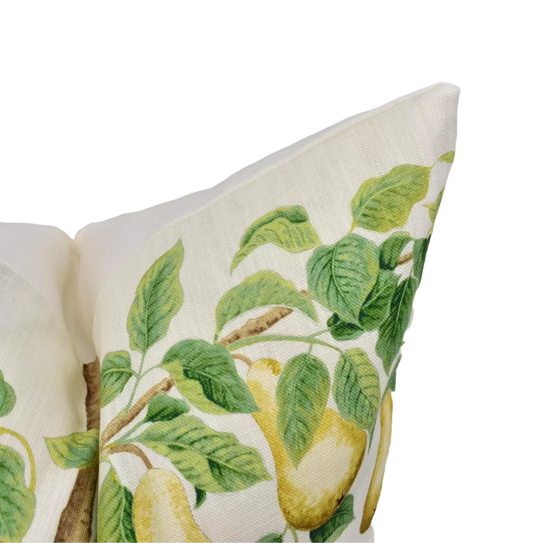 A close-up view of a white pillow with a green leaf pattern and a yellow fruit pattern, resembling a pear.