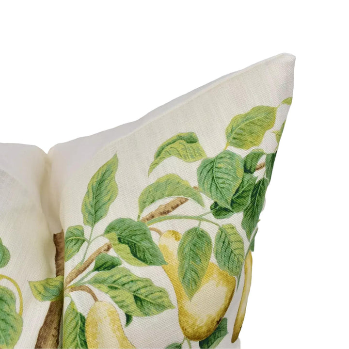 A close-up view of a white pillow with a green leaf pattern and a yellow fruit pattern, resembling a pear.