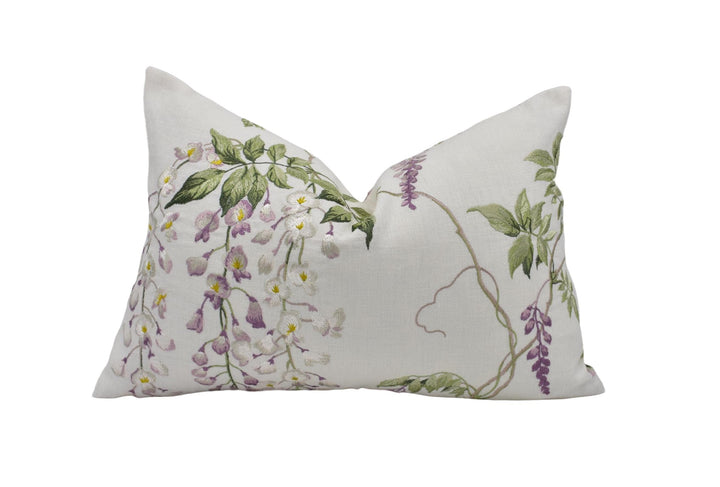 A white pillow with a floral design featuring purple and green flowers and leaves.