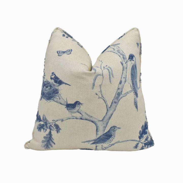 a beige pillow with a blue and white bird and leaf pattern.