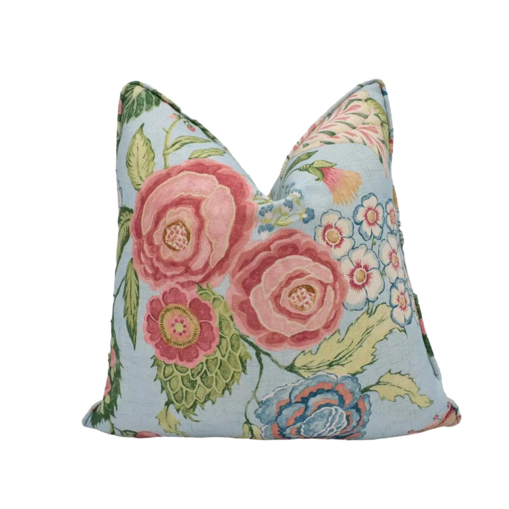 A decorative pillow with a floral pattern in shades of pink, blue, and green.