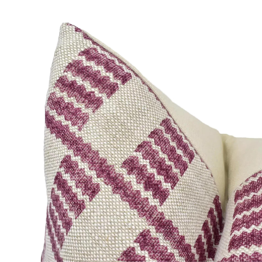 a close-up view of a decorative pillow with a geometric pattern in shades of pink and beige.